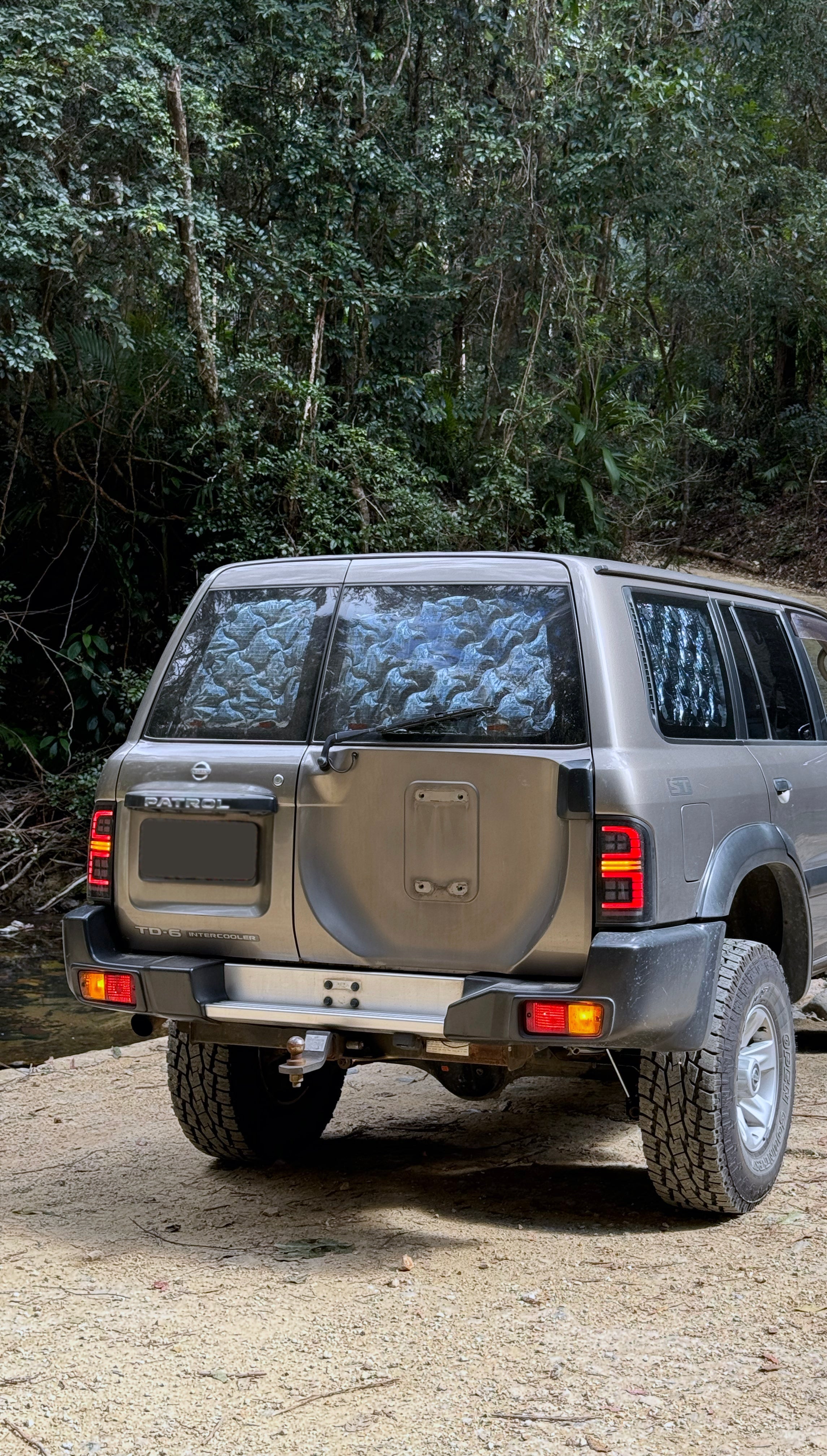 Gray SUV on a dirt road with trees in the background